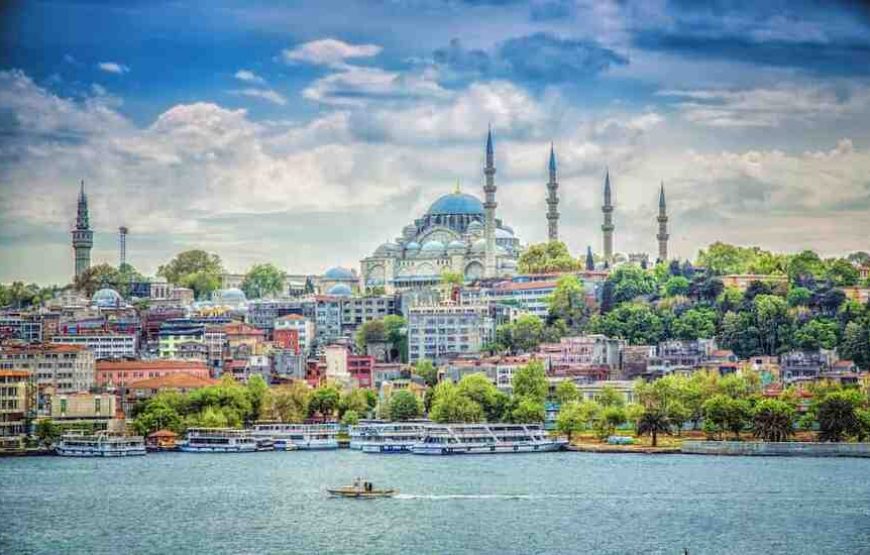 Suleymaniye Mosque's majestic domes and minarets seen from Eminonu, Istanbul, against a blue sky.