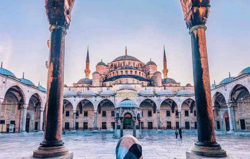 The inner courtyard of the Blue Mosque in Istanbul, featuring intricate arches, domes, and a central fountain.