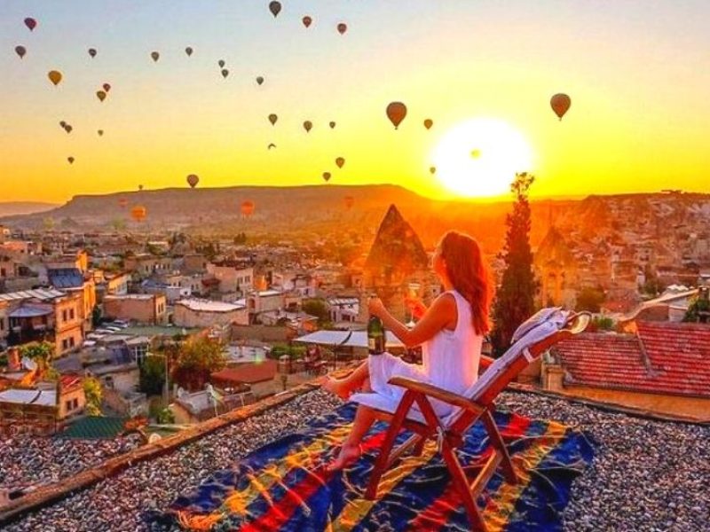 A panoramic view from a hotel terrace in Cappadocia, with hot air balloons floating over the scenic landscape.