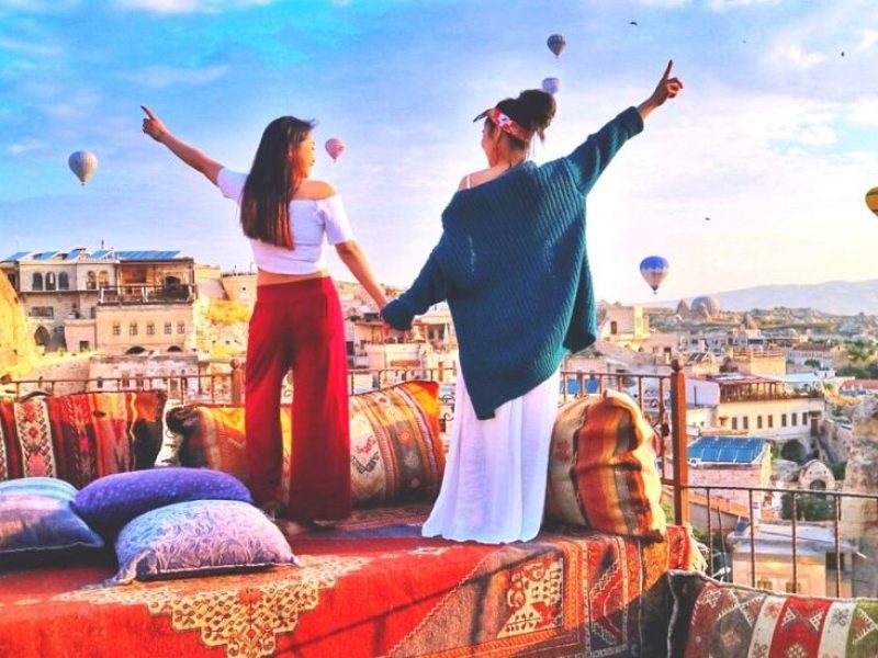 Spectators watching hot air balloon ride in Cappadocia's skyline against the dawn sky.