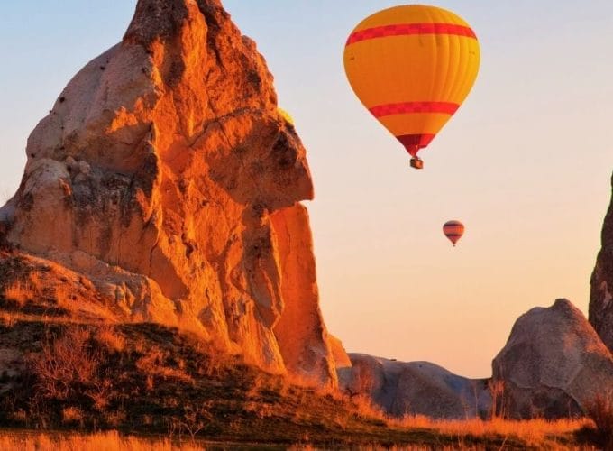 Hot air balloons soaring above the unique rock formations of Cappadocia at sunrise.