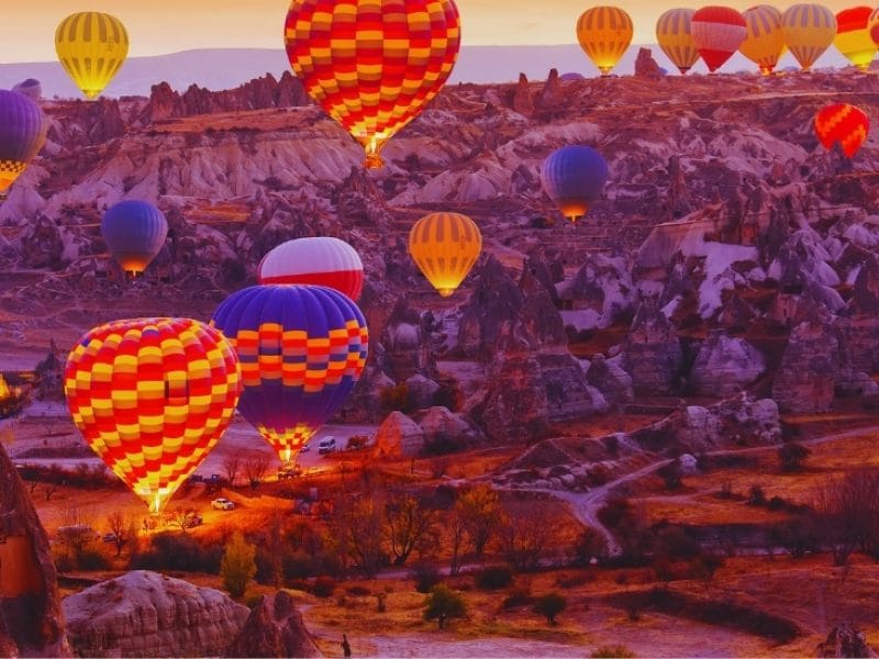 Colorful hot air balloons floating over Cappadocia’s unique landscapes during sunrise.